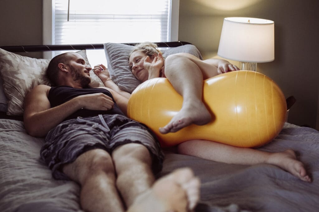 Tifton, Georgia birth photography: Husband and wife relax in bed and gaze at each other in a quiet moment during labor