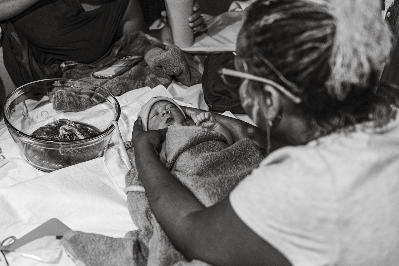 Things your doctor might not tell you about giving birth, Tifton birth photography: midwife checks newborn baby wrapped in towel