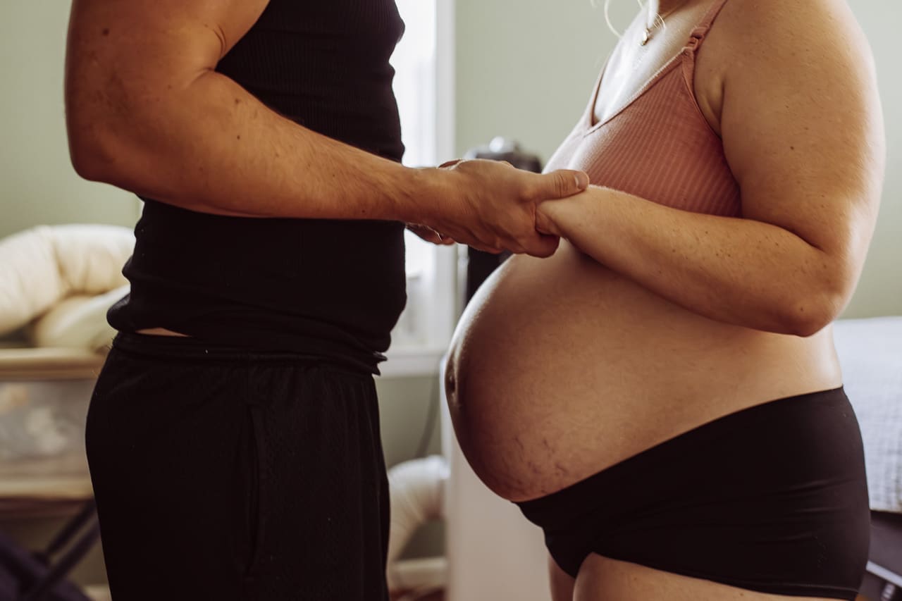 Tifton, GA birth photography: a pregnant woman and her husband face each other holding hands over her belly