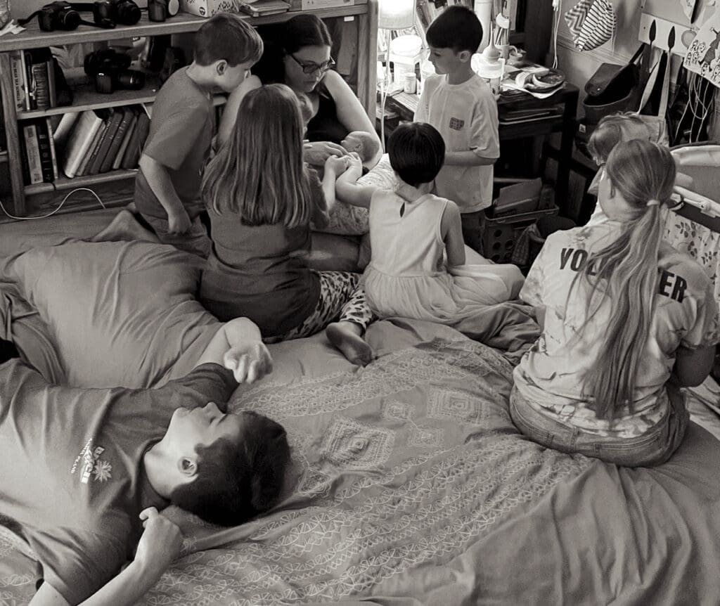Tifton birth photographer: Mom holding newborn, surrounded by siblings meeting it for the first time