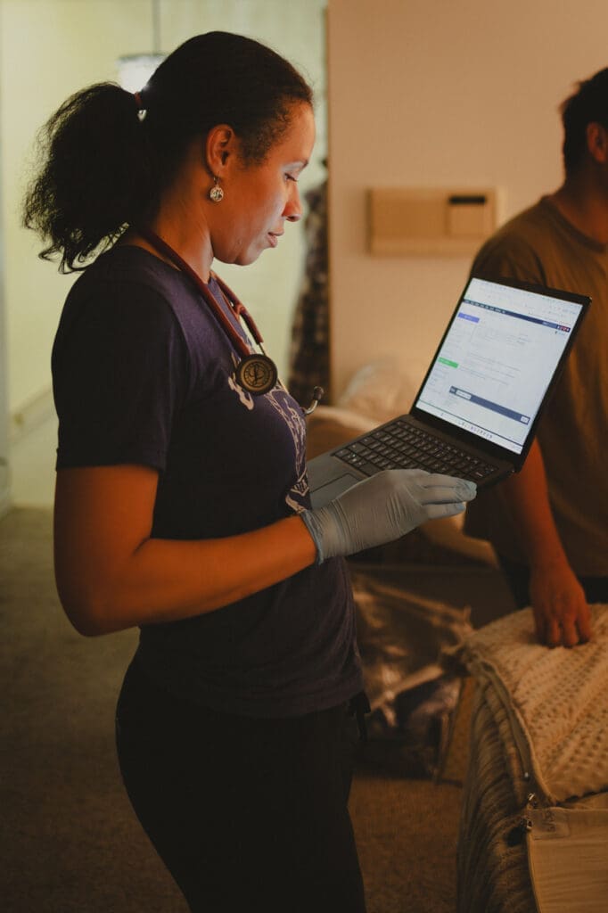 Why more families are choosing home birth: midwife Victoria Gordon updates charts on her lap top in a family's home just after delivering a baby