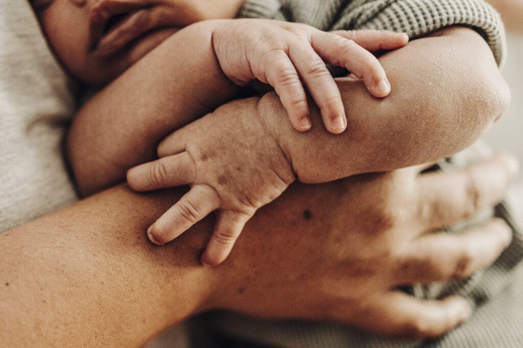 Close-up of newborn hands resting on parent’s arm during postpartum recovery in South Georgia