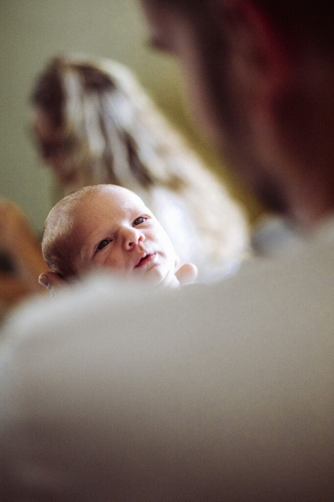 Postpartum mental health: Newborn baby resting in parent’s arms during early postpartum days at home by Tifton birth photographer